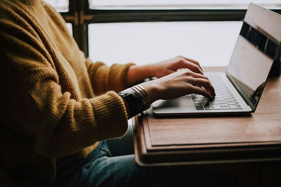 Eine Person sitzt an einem Laptop und tippt auf einer Laptop-Tastatur.